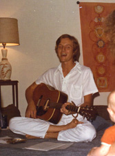Picture of David sitting cross-legged with an acoustic guitar